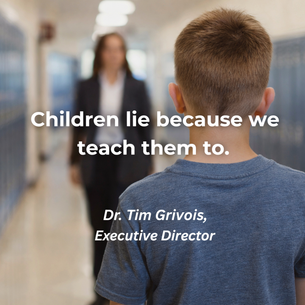 A child standing alone in a school hallway, viewed from behind, with an adult figure out of focus in the background.